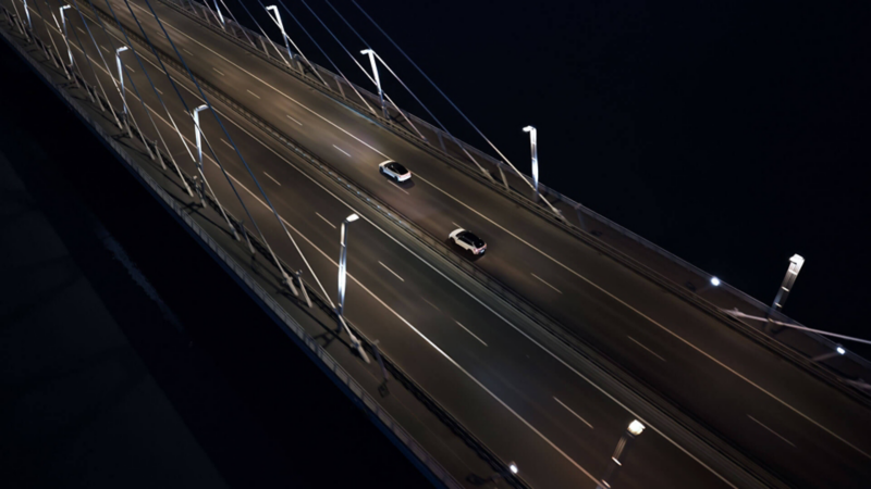 Deux véhicules circulent de nuit sur une autoroute.