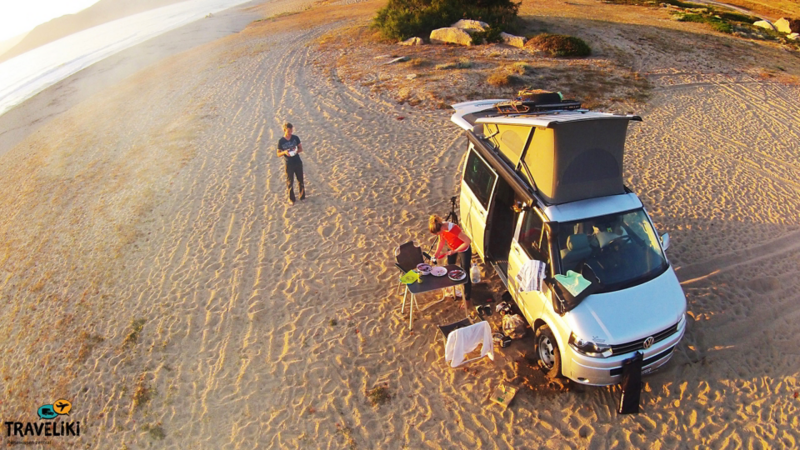 Ein Mann und eine Frau Campen am Strand mit dem VW California