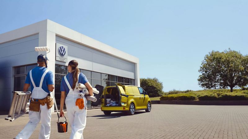 Two decorators walking towards an ID. Buzz Cargo parked outside a VW van centre. 