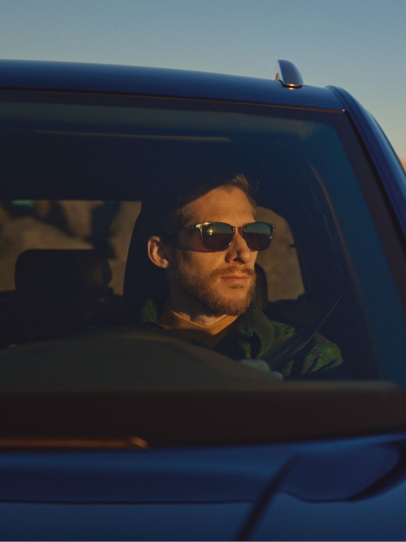 Chico con gafas de sol al volante de un T-Roc R azul