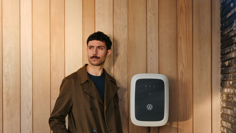 Chico mirando a la cámara apoyada sobre una pared ocre con un ID.Charger de Volkswagen