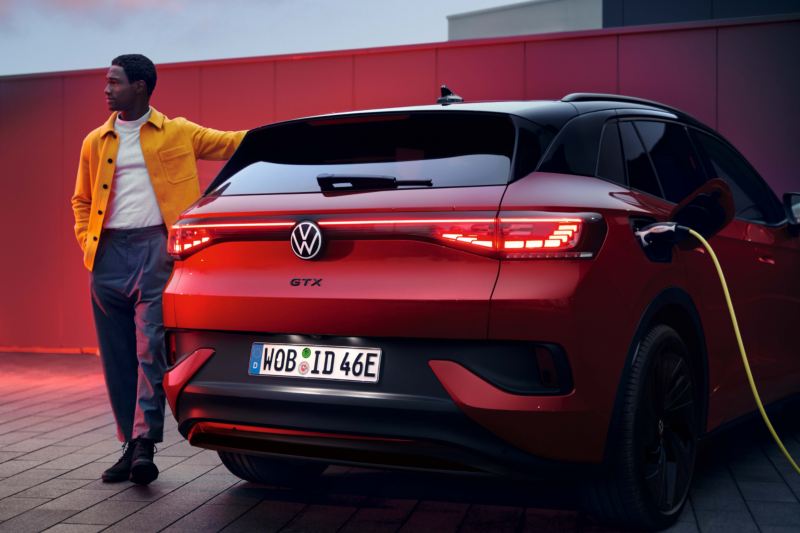 Volkswagen ID.4 GTX en rojo visto por detrás mientras carga. Un hombre está de pie junto al vehículo.