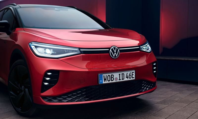 Volkswagen ID.4 GTX en rojo con la puerta del conductor abierta. Una mujer está ante la puerta, mirando al frente.