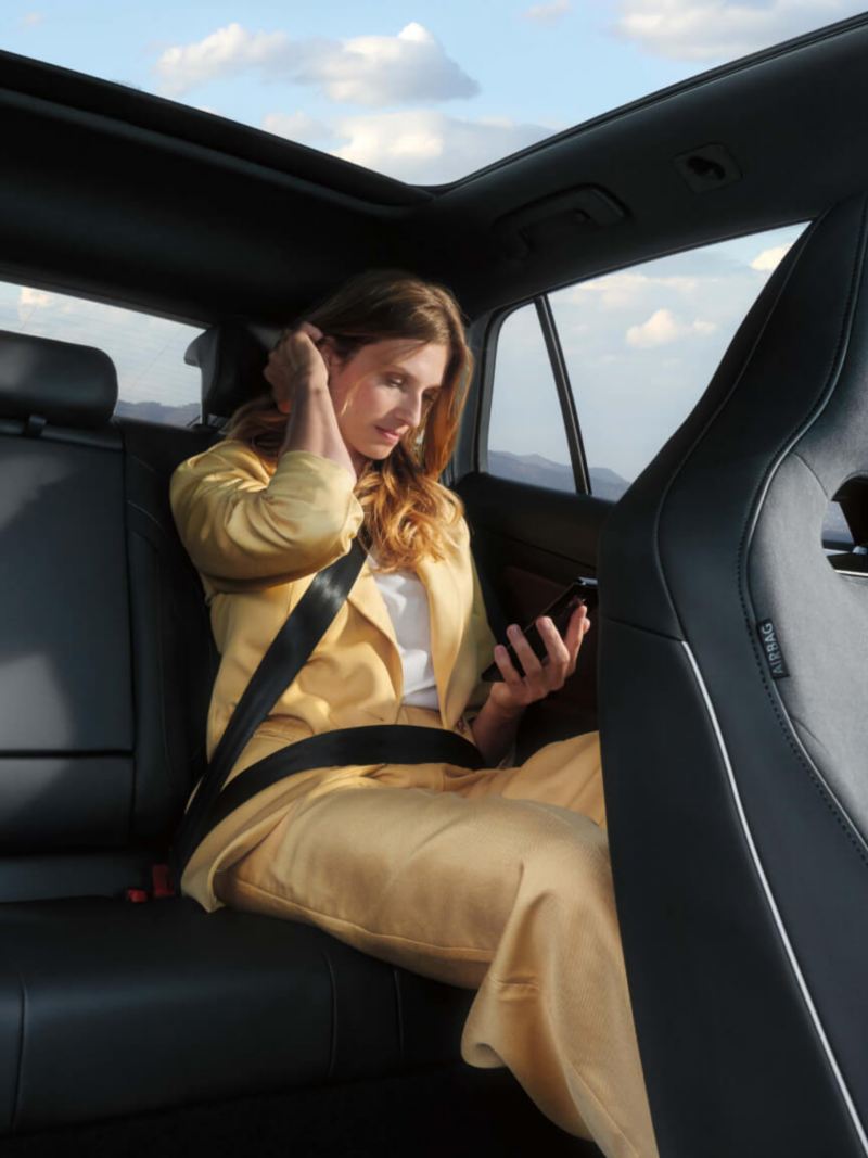Chica dentro de un Volkswagen ID.5 gris mirando el móvil.