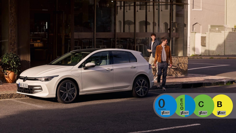 Dos chicos al lado de un Volkswagen Golf de color blanco con las etiquetas DGT