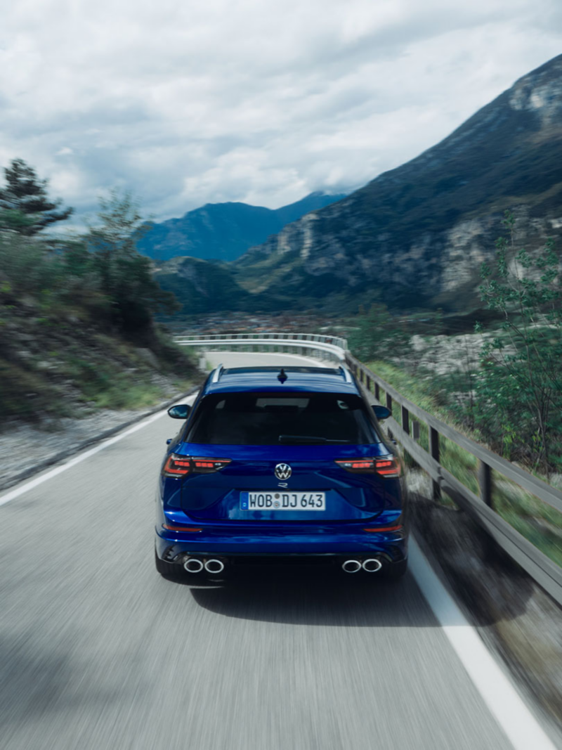 Vista trasera de un Volkswagen Golf 8 Variant R azul circulando por una carretera de montaña