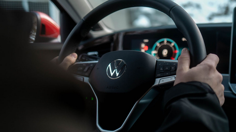 Primer plano de unas manos en un volante e un Volkswagen