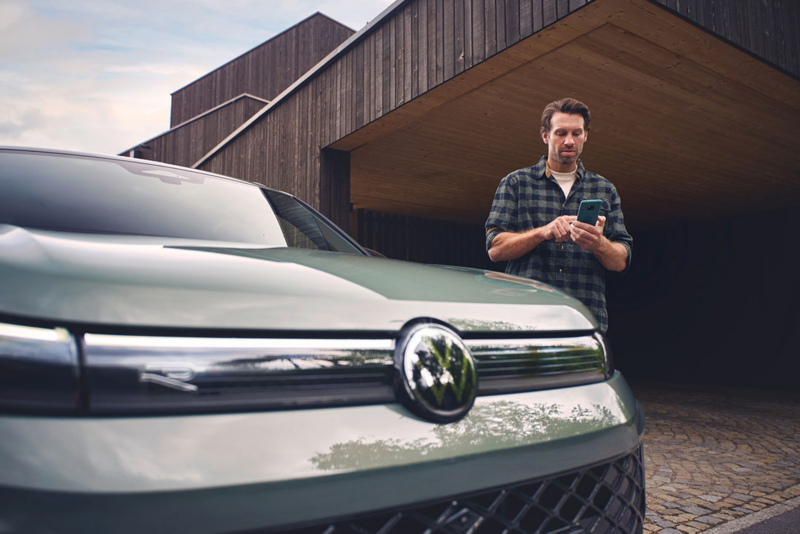 Una persona con un móvil en la mano junto a un Volkswagen SUV