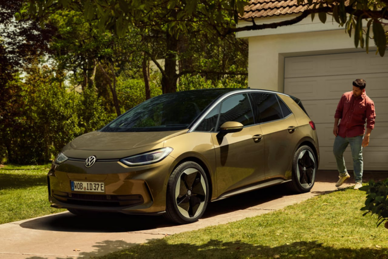 Un hombre detrás de un Volkswagen ID.3 de color ocre estacionado delante de una casa