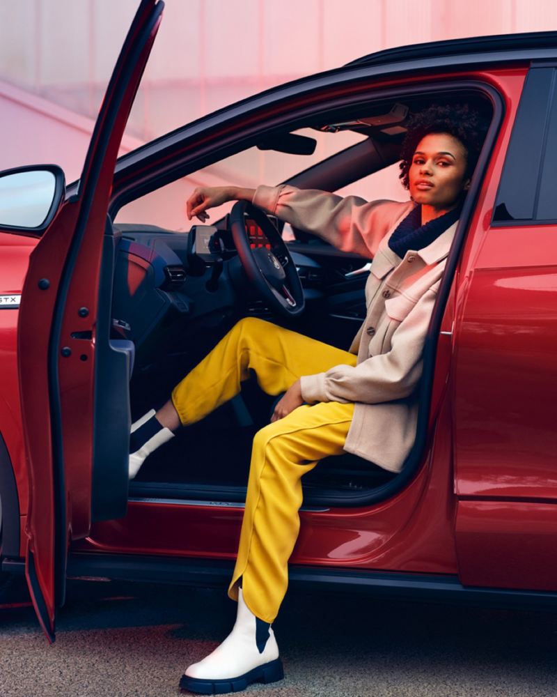 Chica sentada en el puesto de conducción de un Volkswagen ID.4 GTX con la puerta abierta