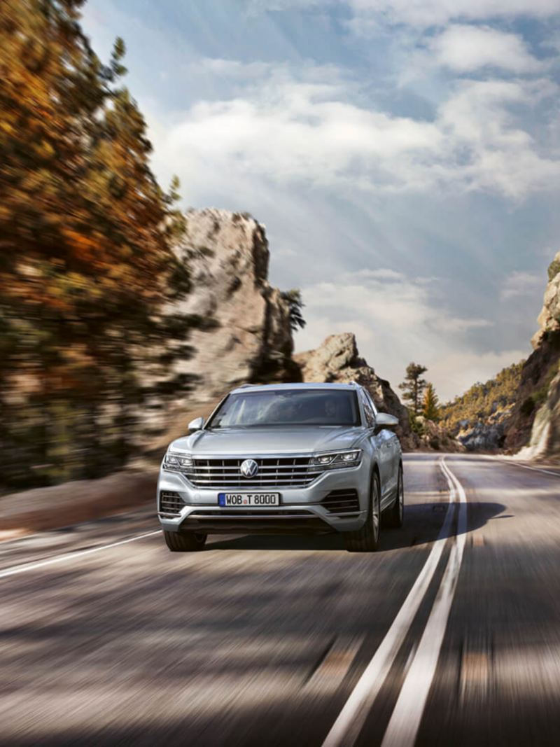 Volkswagen Touareg gris visto de frente en una carretera de montaña