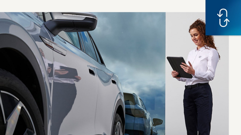 Una trabajadora mirando una tablet en el exterior de un Concesionario Volkswagen