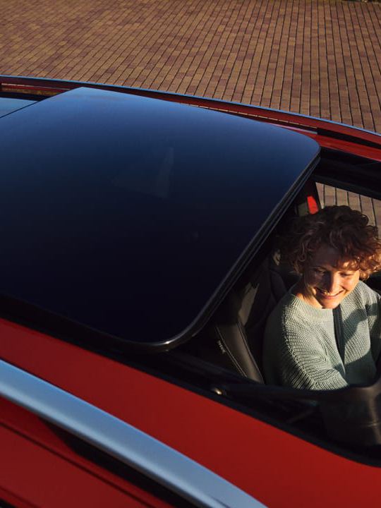 Chica vista a través del techo solar panorámico de un Volkswagen Tiguan rojo