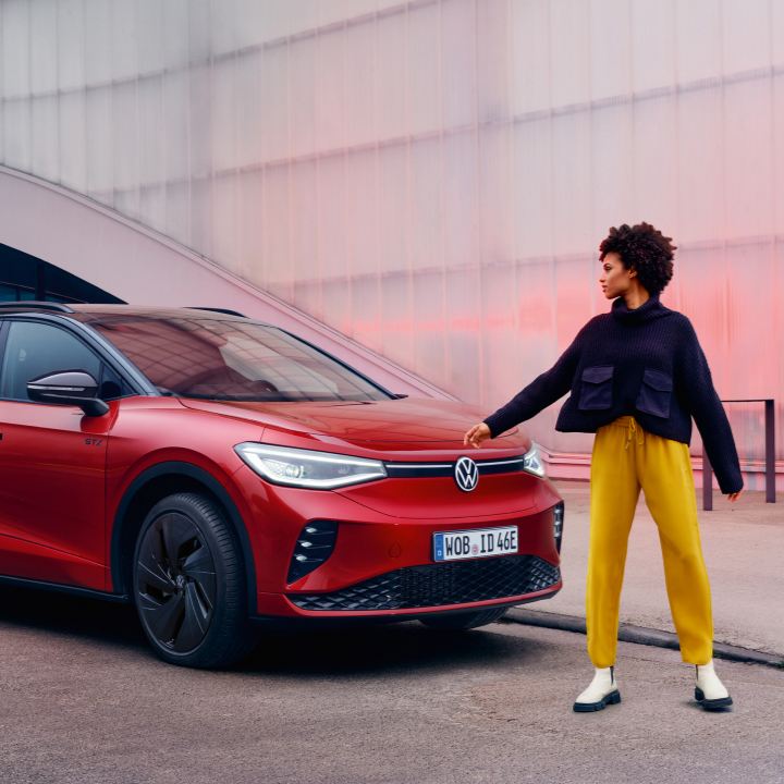 Una chica junto a un Volkswagen de color rojo