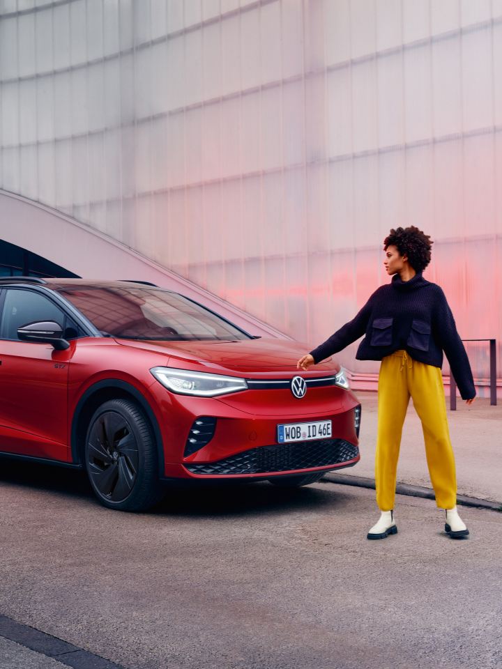 Una chica junto a un Volkswagen de color rojo