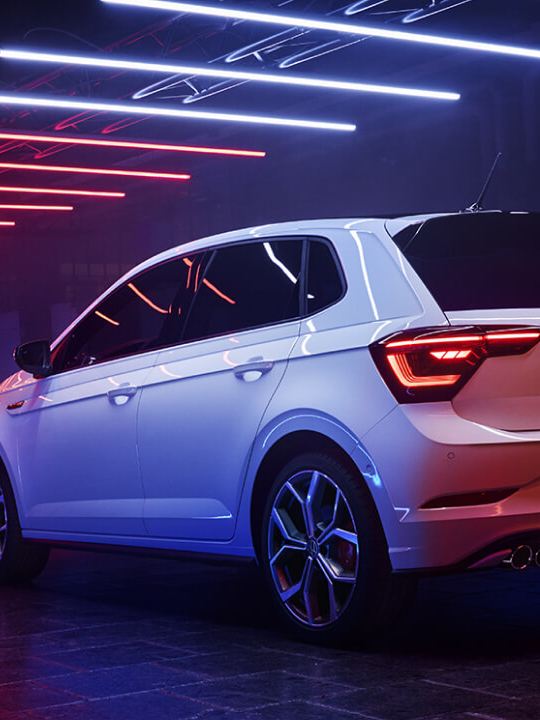 Vista trasera de un Volkswagen Polo GTI en una nave con luces azules y rojas