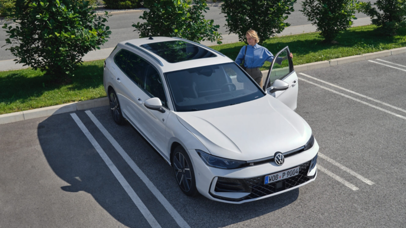 mujer abriendo la puerta de un Volkswagen Passat Variant blanco estacionado el aparcamiento