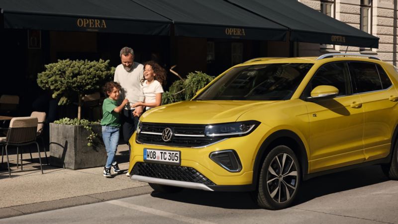 Família sonriendo junto a Volkswagen T-Cross amarillo estacionado en la calle