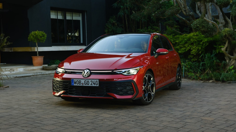 Volkswagen Golf de color rojo estacionado junto un jardín