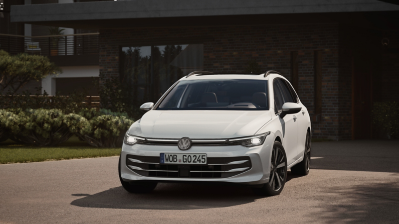 Un Volkswagen golf variant de color blanco estacioando delante de una casa