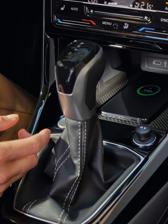 Detalle de una mano y un móvil en salpicadero de un Volkswagen T-Cross