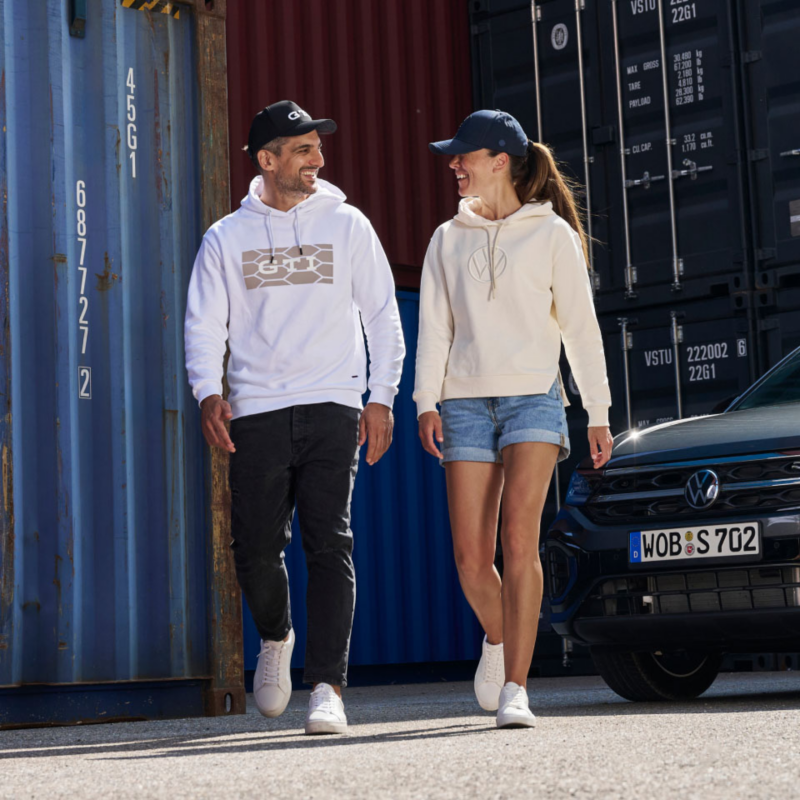 Una pareja caminando entre un contenedor y un Volkswagen
