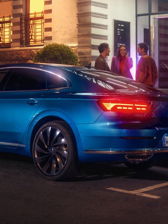 Vista trasera de un Nuevo Volkswagen Arteon azul aparcado en la calle por la noche