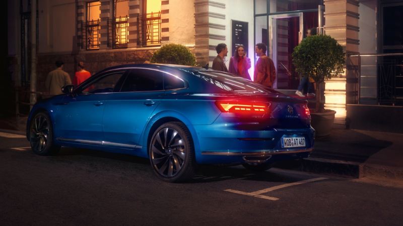 Vista trasera de un Nuevo Volkswagen Arteon azul aparcado en la calle por la noche