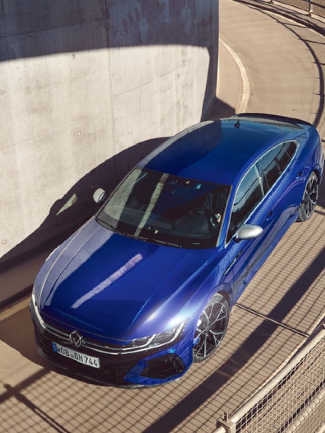 Vista superior de un Nuevo Volkswagen Arteon R azul bajando por una curva