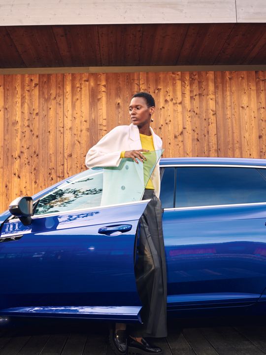 Chica bajando de un Nuevo Volkswagen Arteon Shooting Brake R azul visto de costado