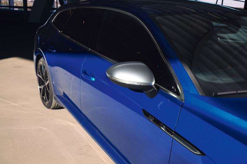 Detalle de un espejo retrovisor y el costado de un Nuevo Volkswagen Arteon Shooting Brake R azul