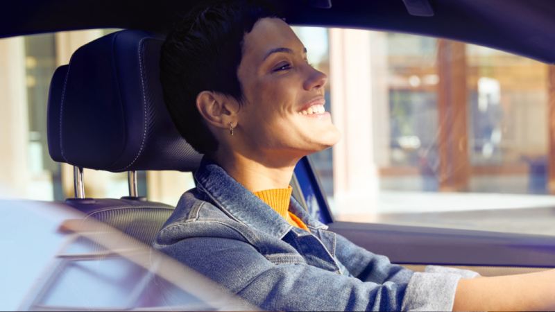 Chica sonriendo al volante de un Volkswagen