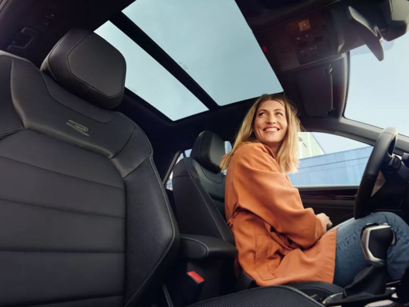 Una chica sonriendo al volante de un Volkswagen Tiguan