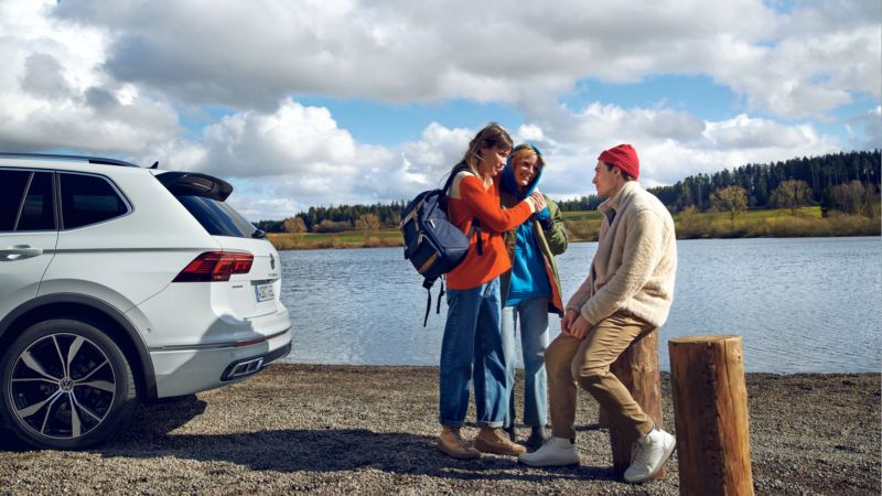 Grupo hablando junto a un lago detrás de un SUV Volkswagen
