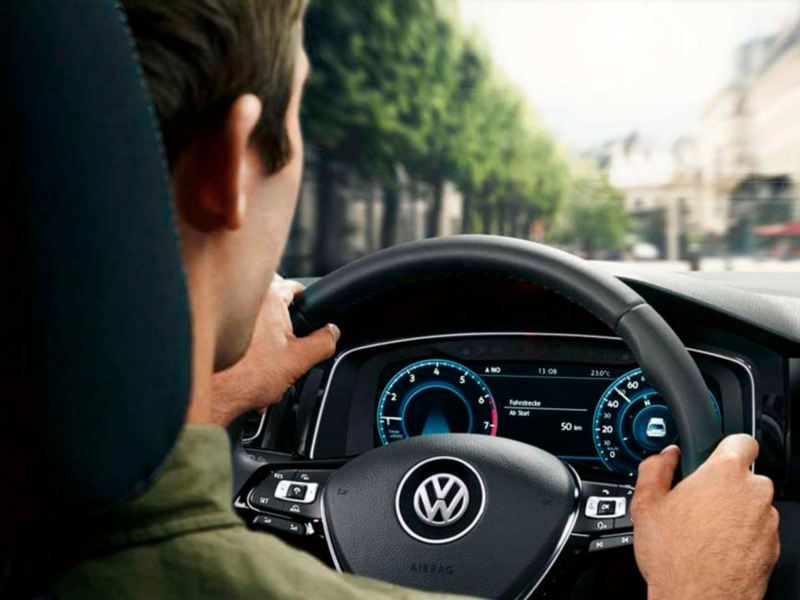 Hombre joven visto desde atrás conduciendo un Volkswagen en la ciudad