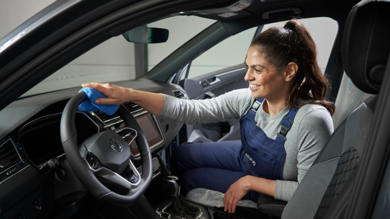 Mecánica limpiando el interior de un Volkswagen con un paño