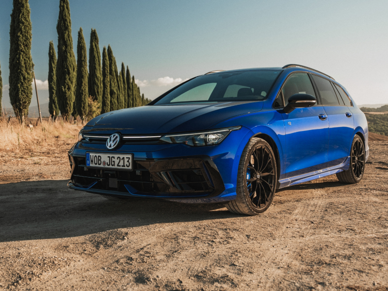 Un Volkswagen de color azul estacionado sobre un pavimento de arena