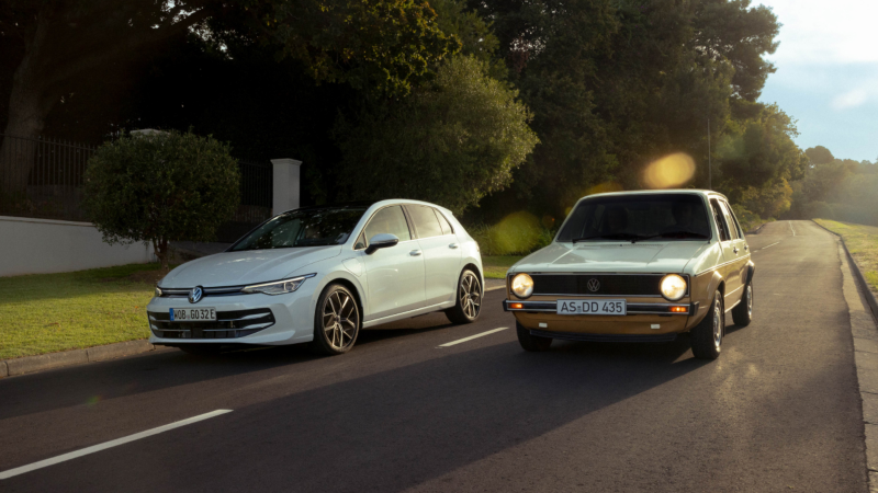 Un Volkswagen golf nuevo blanco y otro viejo gris circulando por una carretera