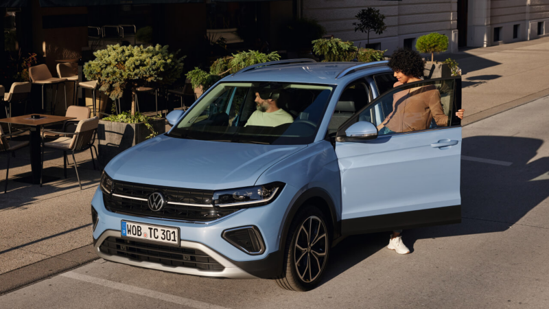 Dos personas subiendo a un Volkswagen T-Cross azul aparcado, accesorios Volkswagen