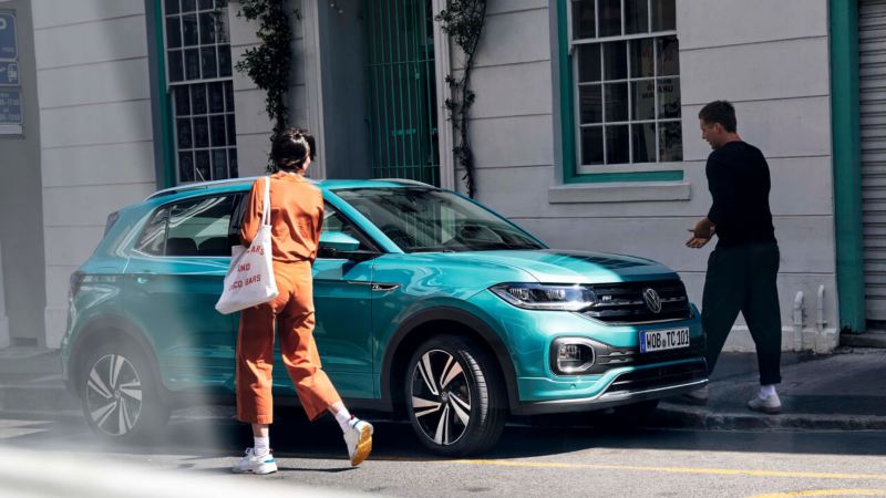 Una pareja unto a un Volkswagen T-Cross esmeralda aparcado en la calle