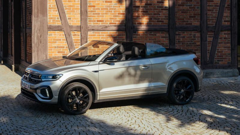 Una chica con una maleta junto a un Volkswagen T-Roc Cabrio, accesorios Volkswagen