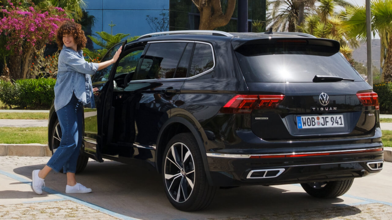 Una chica subiendo a un Volkswagen Tiguan Allspace aparcado, accesorios Volkswagen