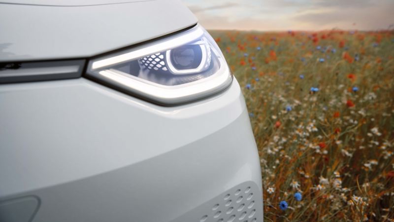 Detalle del faro de un Volkswagen ID.3 blanco junto a un campo de flores