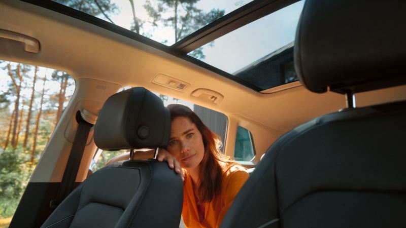 Chica en el interior de un Volkswagen en un bosque que se ve a través de las ventanas