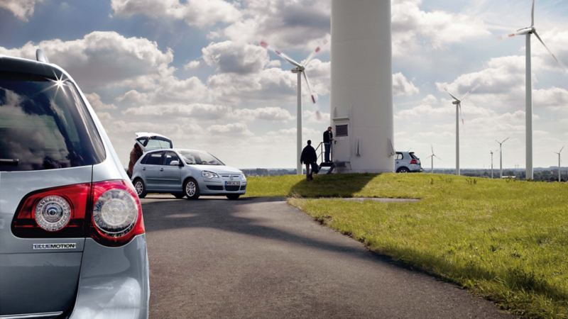 Vehículos eléctricos de Volkswagen aparcados junto a un parque eólico