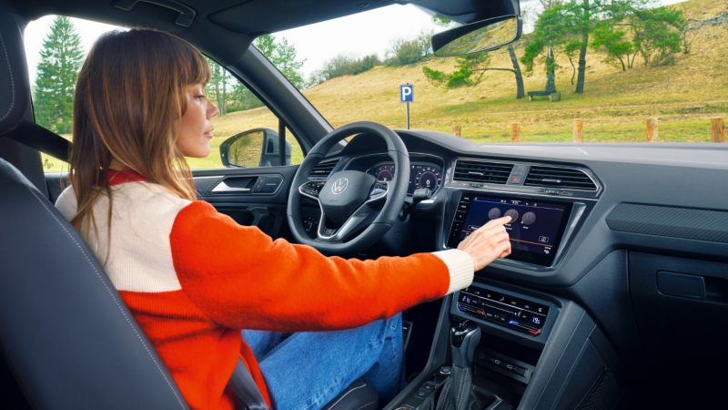 Una chica al volante de un Volkswagen SUV en el campo