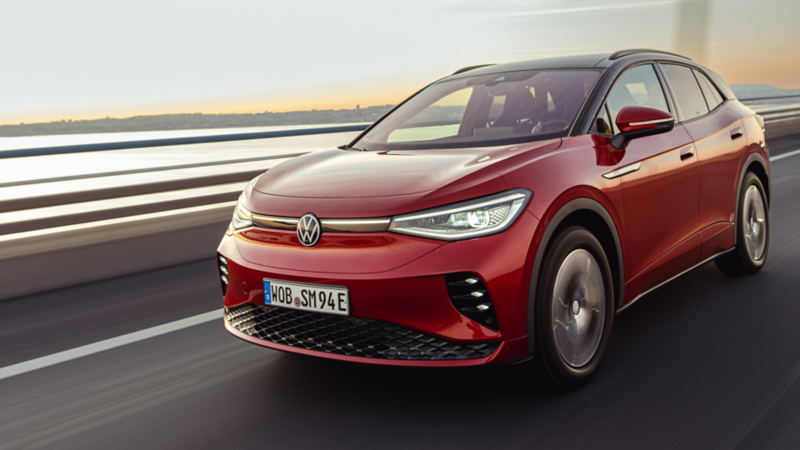 Volkswagen ID. 5 rojo en una autopista junto al mar con una ciudad de fondo