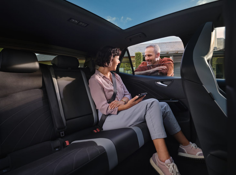 Una mujer sentada en la parte posterior de un Volkswagen un un hombre asomado a la ventana