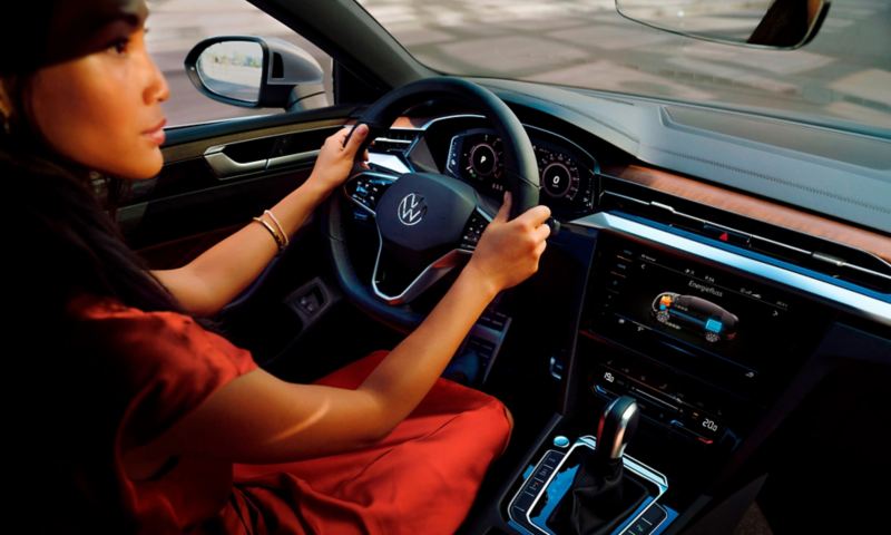 Chica de rojo al volante de un Volkswagen Arteon hibrido enchufable