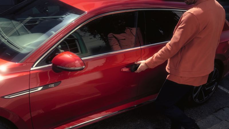 Hombre abriendo la puerta del conductor de un Arteon Shooting Brake rojo